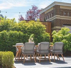 a group of chairs sitting around a wooden table in the middle of a courtyard area