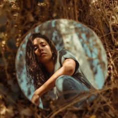 a woman sitting in front of a round mirror