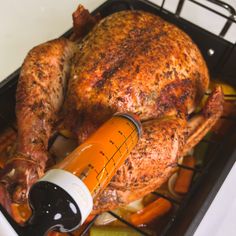 a large chicken sitting on top of a pan filled with vegetables next to a thermometer