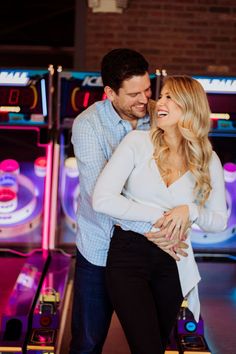 a man and woman standing next to each other in front of a bowling alley with neon lights