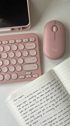 a pink keyboard, mouse and cell phone on a white desk with notepad next to it