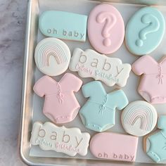 baby shower cookies in a metal tray on a marble counter top with the words, baby and rainbows