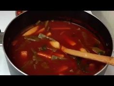 a pot filled with stew and vegetables on top of a stove next to a wooden spoon