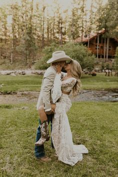 a bride and groom kissing in front of a cabin on the side of a river