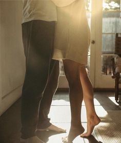 a man and woman standing next to each other in front of a door with sunlight streaming through them