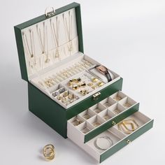 an open green jewelry box with rings and bracelets