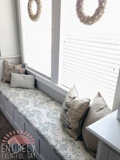 a window seat with pillows and wreaths on the windowsill