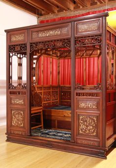 an ornate wooden room divider with red curtains