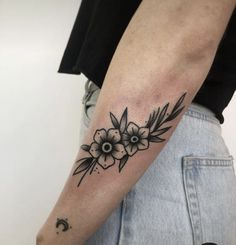 a black and white flower tattoo on the left arm, with an arrow in the middle