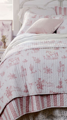 a bed with pink and white bedspread, pillows and blankets on top of it