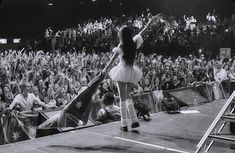 a woman standing on top of a tennis court holding a racquet in front of a crowd