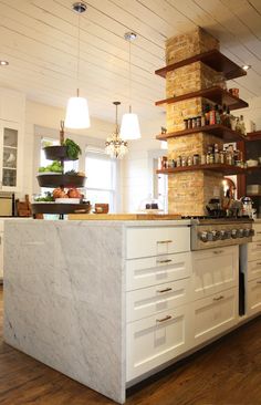 a large kitchen with an island in the middle and shelves on the wall above it