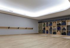 an empty room with wooden floors and shelves filled with blue vases on the wall