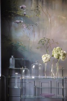 three vases with flowers on top of a shelf in front of a wall mural