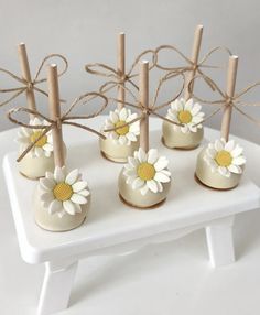 small white vases with daisies tied in twine on a tray for display