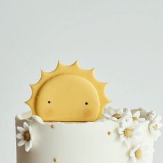 a white cake topped with a sun and daisies