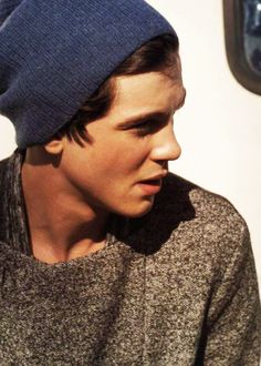 a young man wearing a blue beanie looks off into the distance