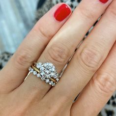 a woman's hand with red nail polish and two engagement rings on her fingers