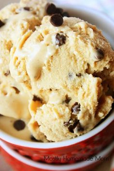 two scoops of ice cream with chocolate chips in a red and white cup on a table