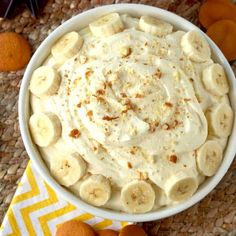 a white bowl filled with bananas on top of a yellow and white napkin next to oranges