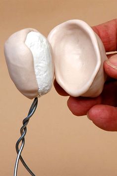 a hand is holding an object that looks like two white balls on a wire, with one being held by the other