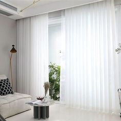 a living room with white curtains and black accents