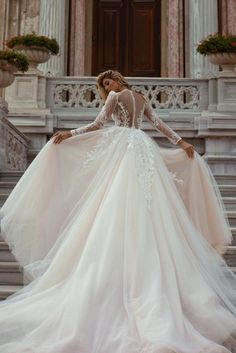 a woman in a wedding dress standing on some steps with her back to the camera