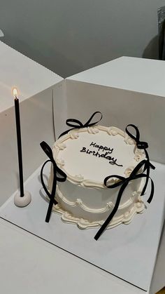 a birthday cake sitting on top of a white box with a lit candle in it