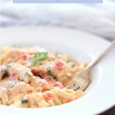 a white bowl filled with pasta and meat on top of a wooden table next to a fork