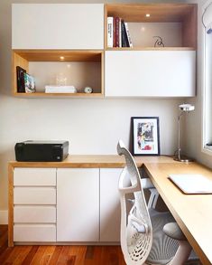 an office with white cabinets and wood floors, including a printer on a desk in front of a window