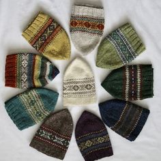 six knitted mittens arranged in a circle on a white surface, with different colors and patterns