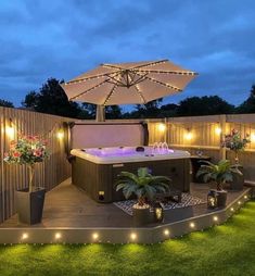 an outdoor hot tub surrounded by lights and potted plants