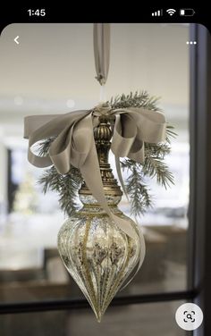 a christmas ornament hanging from a window with a bow on it's head