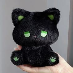 a black cat with green eyes is holding in someone's hand and it looks like they have been stuffed