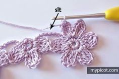 the crochet flower is being worked on by a knitting hook and yarn needle