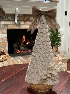 a small white christmas tree sitting on top of a wooden table next to a fire place