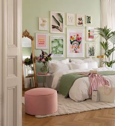 a bedroom decorated in pastel green and white with pictures on the wall above the bed