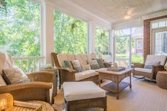 a screened porch with wicker furniture and large windows