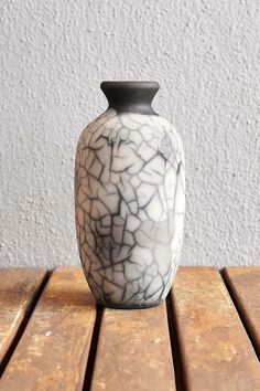 a black and white vase sitting on top of a wooden table