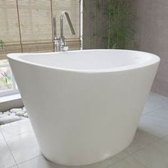 a large white bath tub sitting on top of a tiled floor next to a window