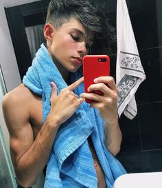 a young man is taking a selfie in the bathroom with his cell phone while wearing a blue towel