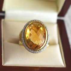 Vintage cocktail ring by jeweler David Yurman crafted in 18-karat yellow gold. It features a checkerboard-cut citrine weighing approximately 12.5 carats (18.0 x 13.0 x 8.0 mm), surrounded by a double halo of brilliant-cut diamonds totaling about 1 carat, with G/H color and VS clarity. The ring's band has a twisted design, and the signature "D.Y" for David Yurman is found on the inside. Weight: 17.9 g Size: 51 FR (5.75 US - L UK) Metal: 18-karat Yellow Gold Stones: citrine (approx. 12.5 carats) a Luxury Faceted Yellow Ring, Luxury Faceted Topaz Ring, Formal Yellow Gold Citrine Topaz Ring, Formal Yellow Topaz Ring, Formal Yellow Gold Topaz Ring With Diamond Cut, Formal Citrine Diamond-cut Ring, Formal Citrine Diamond Cut Ring, Formal Citrine Ring With Diamond Cut, Luxury Oval Faceted Topaz Ring