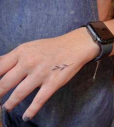 a woman's hand with a small tattoo on it and an apple watch in the background