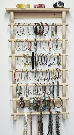 a wooden rack with many bracelets hanging from it's sides on a wall