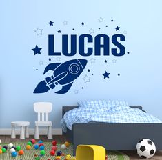 a child's bedroom with a wall decal that says lucas on the rocket ship