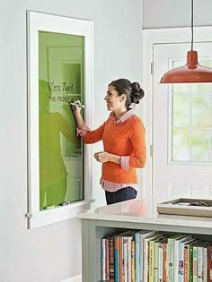 a woman is writing on the wall with a marker and an easel in front of her