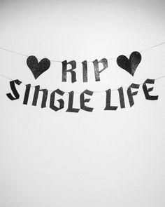 black and white photograph of the words rip single life hanging on a line with hearts