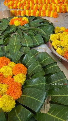 several bowls filled with yellow and orange flowers next to green leaves on the ground in front of them