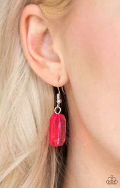 a woman with blonde hair wearing red earrings