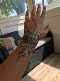 a person's hand with a tattoo on it and a window in the background